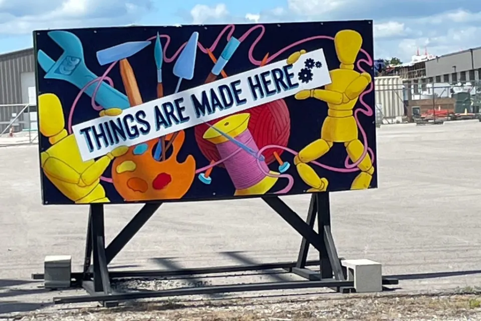 Mural showing tools and craft supplies with banner reading 'Things are made here' in front of makerspace in Columbia, Missouri.
